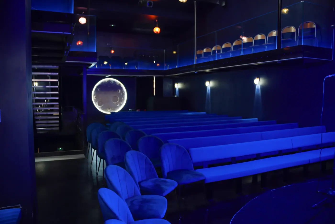 La salle du Marseille Comedy Club en lumière bleue, ses gradins, sa mezzanine et sa lune lumineuse